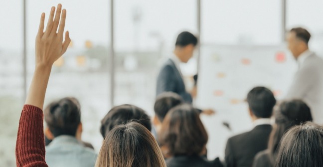 Woman with hand up in a sales meeting