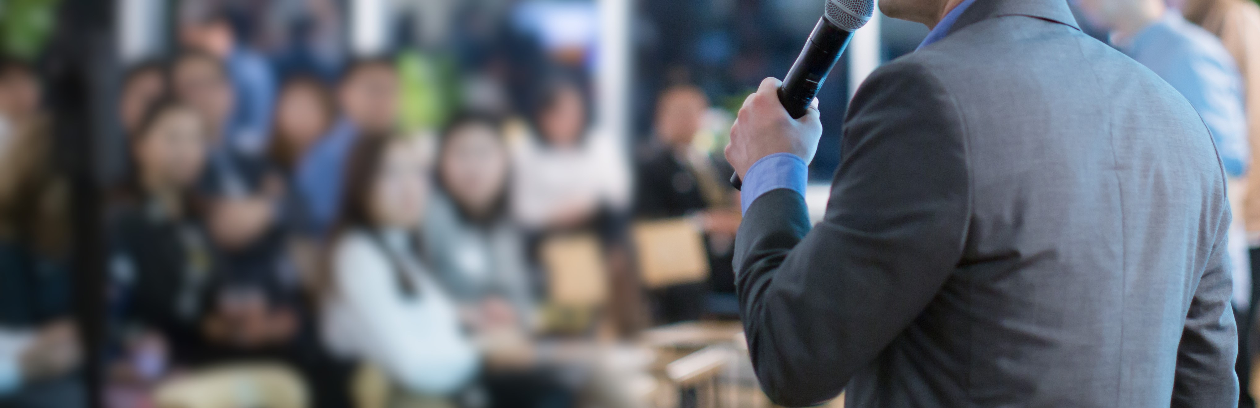 Man holding a microphone addressing a group of people