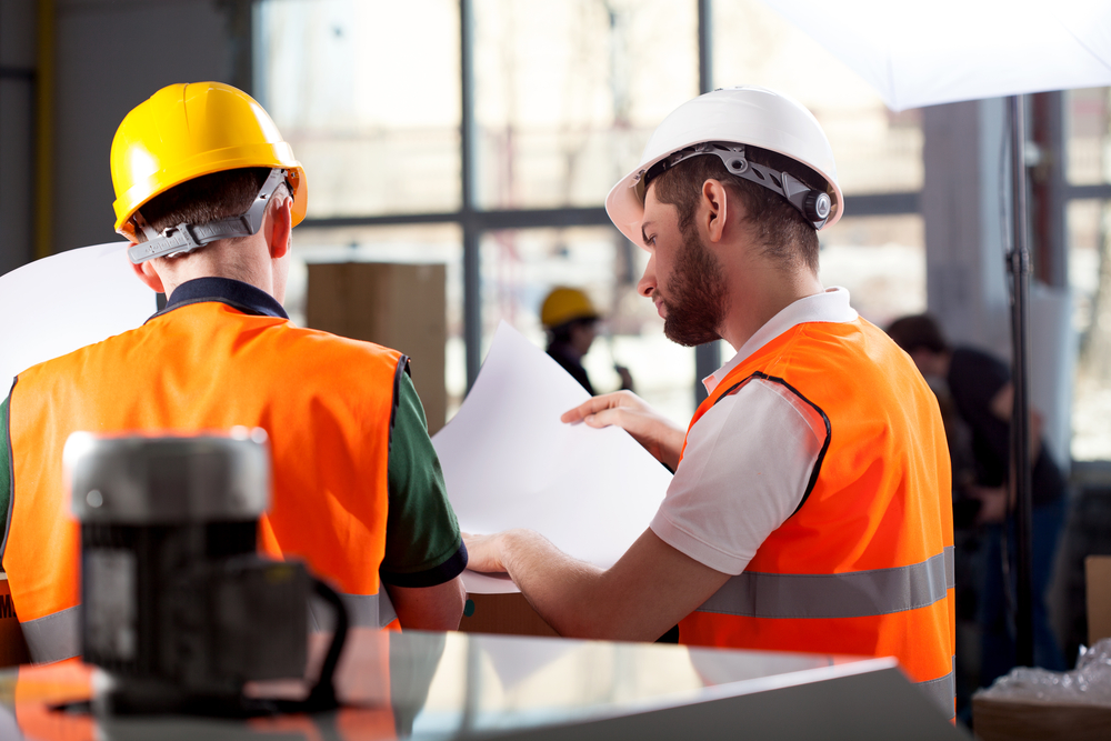 Male factory worker and supervisor are analyzing plans-1